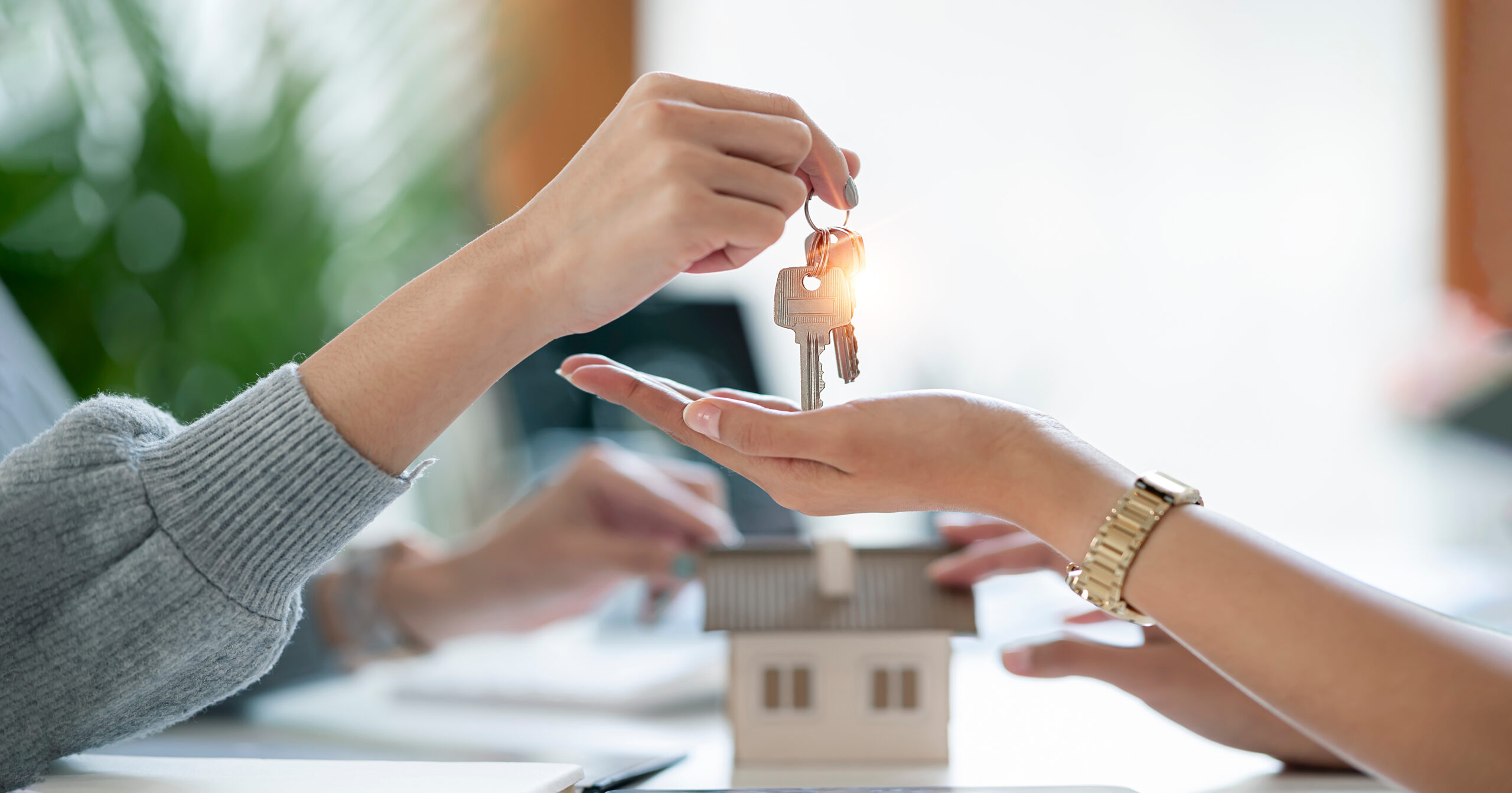 Female realestate agent giving house key to her customer, proper